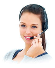 A customer service woman wears a pair of headphones with a microphone and smiles at the camera.