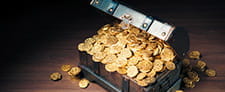 A chest with an open lid overflowing with very shiny gold coins.