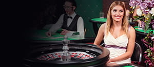 A croupier sitting at a roulette wheel.