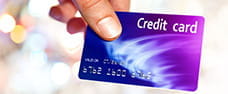 A hand clutches a blue and purple credit card by the corner. In the upper corner of the card is written Credit Card.
