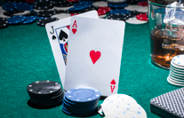 On a table there are two cards and several piles of casino chips.