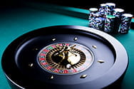 A casino roulette wheel and several stacks of chips.