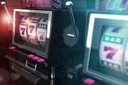 Two traditional slot machines with cranks and a combiner line with red sevens.
