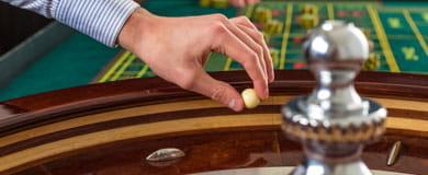 The dealer is about to throw the ball into the wooden roulette cylinder.