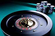 A roulette wheel and several stacks of chips on a casino table.