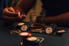 Hand, poker chips and glass of whiskey.