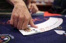 Croupier unfolds a poker deck on the mat.